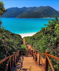 a wooden stairway leading to a lake on a hill at Nossa Casa Arraial HOSTEL e SUÍTE in Arraial do Cabo