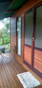 a wooden porch with a bench and a glass door at Cabanas sítio Ancestral in Morretes