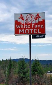 een bord voor een wit boerderijmotel op een paal bij White Fang Motel in Wawa