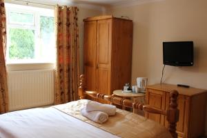 een slaapkamer met een bed, een televisie en een kast bij Remarc Guest House in Takeley