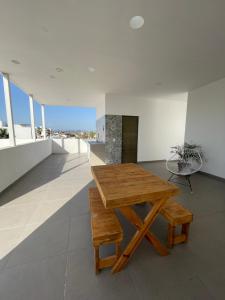 una mesa de madera y un banco en una habitación con ventanas en El Departamento Playa Sur, en Mazatlán