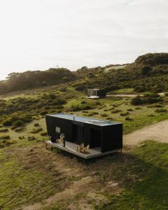 a black house on a hill with two dogs on a bench at CABN Kangaroo Island in Penneshaw