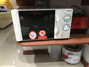 a white microwave sitting on a wooden shelf at StayinManila in Pasig