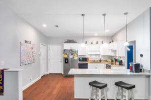 a kitchen with white cabinets and black stools at Verb - Arcades, Grill, Gym, Piano, Pong, & Beach! in Fort Walton Beach