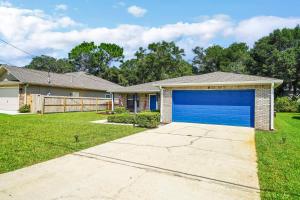 a house with a blue garage at Verb - Arcades, Grill, Gym, Piano, Pong, & Beach! in Fort Walton Beach