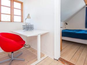 Holiday home Grenaa XLVIII في جرينا: كرسي احمر في غرفة مع مكتب وسرير