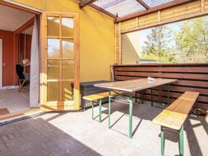 un patio con tavolo in legno e panche di Holiday home Grenaa XLVIII a Grenå