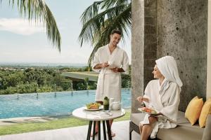 Ein Mann und eine Frau sitzen auf einer Terrasse mit einem Tisch in der Unterkunft Four Points by Sheraton Bali, Ungasan in Jimbaran