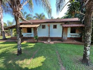 een huis met palmbomen ervoor bij Pousada Fazenda São Pedro in Delfinópolis