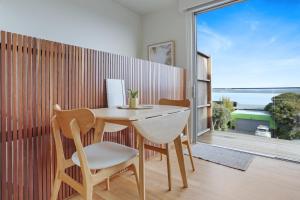 a table and chairs in a room with a large window at Sea Change and Studio on Tasman in Merimbula