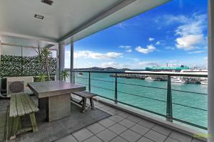 einen Balkon mit einem Tisch und Stühlen sowie Blick auf das Wasser in der Unterkunft QV Upmarket Waterfront Apartment - 787 in Auckland