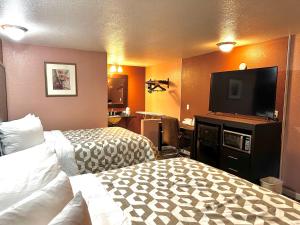 a hotel room with two beds and a flat screen tv at Annie Oakley Motel Oakley in Oakley