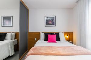 a bedroom with a large bed with a pink pillow at Housi Brickell One - HBO0105 in Curitiba