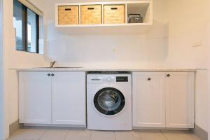 a white laundry room with a washing machine in it at Salty in Quindalup