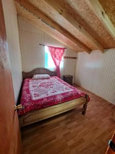 een slaapkamer met een bed met een rood dekbed en een raam bij Normita cabaña in Villa Cerro Castillo