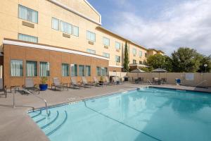 a pool in front of a hotel with chairs and a building at Fairfield Inn & Suites San Angelo in San Angelo