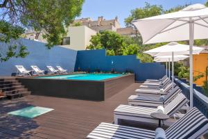 - une piscine avec des chaises et des parasols à côté d'un mur bleu dans l'établissement Casa da Marechal - Boutique Hotel by Oporto Collection - Adults Only, à Porto