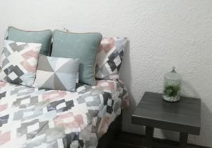 uma cama com almofadas e uma mesa com uma garrafa em Disfruta de cómodo y bello departamento em Guadalajara
