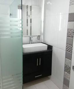 uma casa de banho branca com um lavatório e um espelho em Disfruta de cómodo y bello departamento em Guadalajara