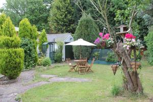 un jardín con mesa, sillas y sombrilla en Remarc Guest House en Takeley