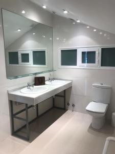 a bathroom with two sinks and a mirror and a toilet at Tajonar Ático Jardín in Tajonar