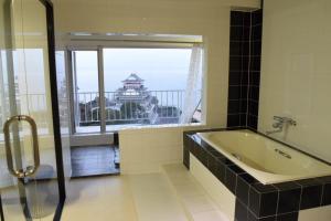 a bathroom with a tub and a window with a view at Mujuan in Atami
