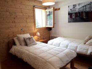two beds in a bedroom with wooden walls at Appartement 8 personnes, piscine, wifi, 4 ch, parking - FR-1-733-123 in Crest-Voland +11 photos