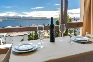 una mesa con una botella de vino y copas en el balcón en Terrazas Bariloche vista en San Carlos de Bariloche