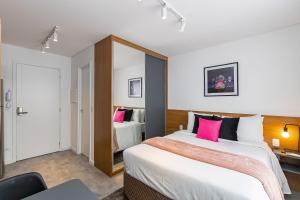 een hotelkamer met 2 bedden en roze kussens bij Housi Brickell One Com Vaga - HBO0606 V12 in Curitiba