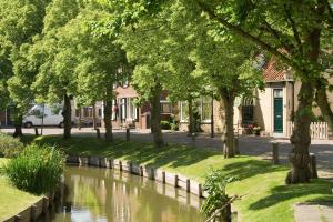 a river in a park with trees and a building at Studio Even dur Uut in Noordgouwe