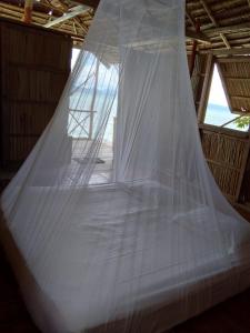 a bed in a room with a mosquito net at Daroyen Village in Kri