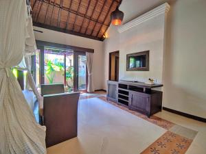 - un salon avec une télévision, une table et un canapé dans l'établissement Barong Resort and Spa, à Ubud