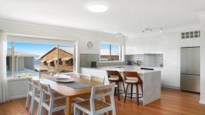 a kitchen and dining room with a table and chairs at Moon Glow Views, Short Walk To Beach Accom Holidays in Terrigal