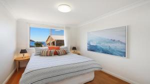1 dormitorio con cama y ventana grande en Moon Glow Views, Short Walk To Beach Accom Holidays en Terrigal