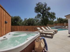 a hot tub sitting on a patio with lounge chairs at Galadriel Villa in Káto Yerakaríon