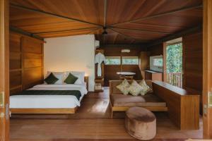 Grün Resort Uluwatu في أُلُواتو: غرفة نوم بسريرين ومقعد في غرفة