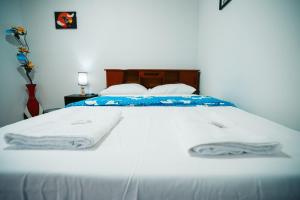 a bed with white sheets and towels on it at POSADA MIS 3 BENDICIONES in Paracas