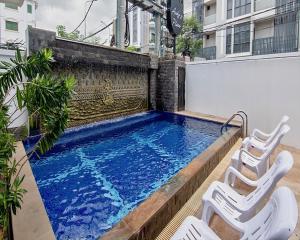 a swimming pool with two white chairs next to a building at Andy's Place in Siem Reap
