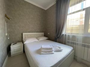 a bedroom with a white bed with towels on it at Keruen Deluxe in Taraz