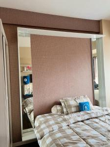 una camera da letto con un letto e un grande specchio di Margonda Residence By Ensroom id a Kemirimuka Dua