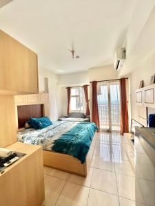 una camera da letto con letto con lenzuola blu e cucina di Margonda Residence By Ensroom id a Kemirimuka Dua