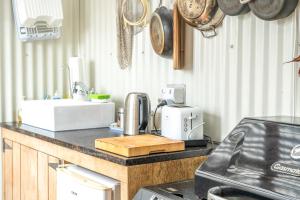 eine Küche mit einer Theke mit einer Spüle sowie Töpfen und Pfannen in der Unterkunft Koru Cabin in Oneroa