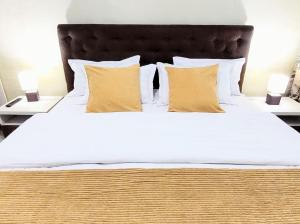 a large bed with white sheets and yellow pillows at Simona Apartament Palas Mall 1 in Iaşi