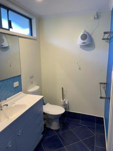een badkamer met een toilet, een wastafel en een spiegel bij Sail House overlooking Lancelins main park in Lancelin