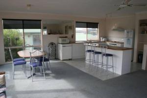 cocina con mesa y taburetes en The Waters Edge at Tampa, en Cape Woolamai