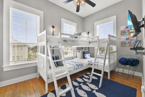2 białe łóżka piętrowe w pokoju z oknami w obiekcie The Sparkled Seahorse w mieście Galveston