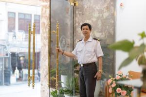 een man voor een gebouw met een gouden paal bij Bao Hung Hotel & Apartment - Tran Quoc Vuong in Hanoi