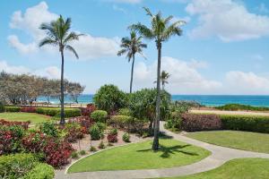 a garden with palm trees and the ocean in the background at Sheraton Grand Mirage Resort Gold Coast in Gold Coast