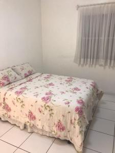 a bed in a bedroom with a floral bedspread at Canal 3 Living - Hospedagem Aconchegante em Santos in Santos