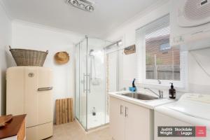 a white kitchen with a sink and a shower at Heyley Haven in Ventnor